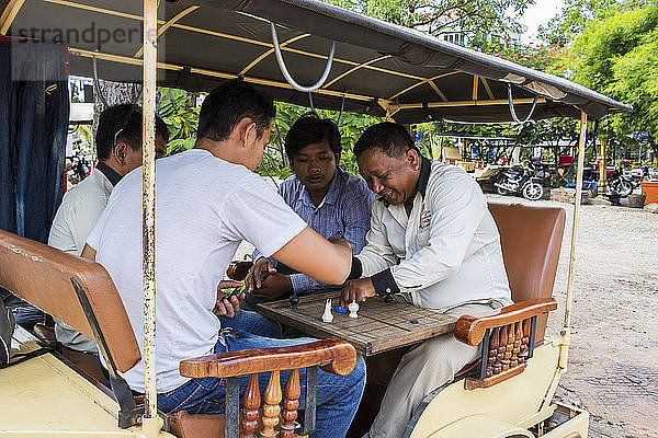 Kambodschanische Männer spielen ein Brettspiel an Bord eines Tuk-Tuk; Siem Reap  Kambodscha