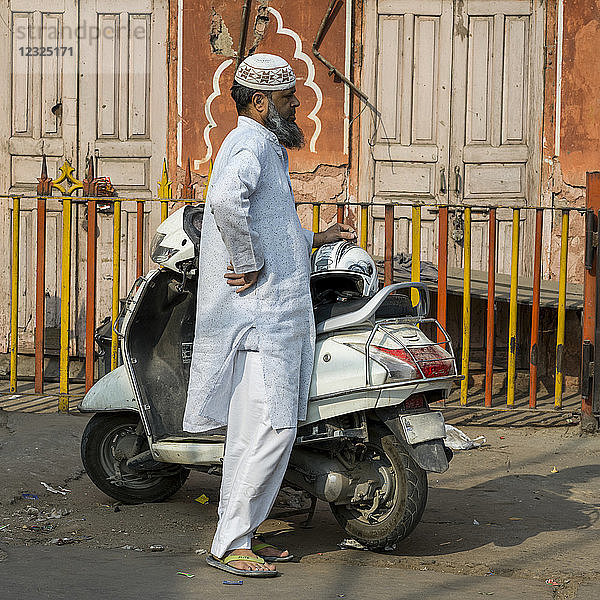 Ein Mann in traditioneller indischer Kleidung steht auf der Straße neben seinem Motorrad; Jaipur  Rajasthan  Indien