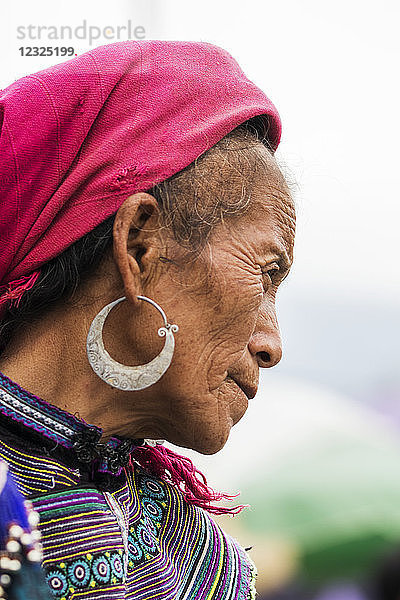 Porträt einer älteren Frau mit Kopftuch und Ohrringen und buntem Kleid; Bac Ha  Lao Cai  Vietnam