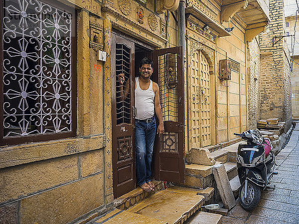Ein indischer Mann steht in der Tür seines Hauses  vor dem ein Motorrad geparkt ist; Jaisalmer  Rajasthan  Indien