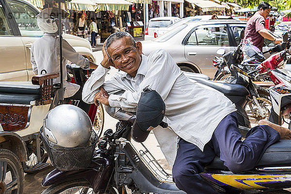 Kambodschaner  der sich auf einem Motorrad ausruht; Siem Reap  Kambodscha