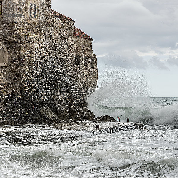 Wellen brechen und plätschern gegen die alten Steinmauern an der Küste von Budva; Budva  Opstina Budva  Montenegro