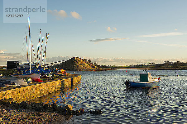 Boote im Hafen mit Blick auf das St. Cuthbert's-Kreuz auf einem Hügel entlang der Küste; Alnmouth  Northumberland  England