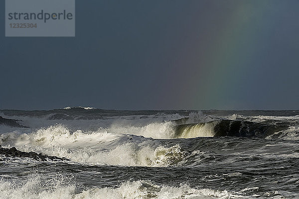 Stürmisches Wetter bringt Dramatik in den Himmel an der Küste von Oregon mit einem Regenbogen aus Farben gegen die dunklen Wolken über den Wellen; Seaside  Oregon  Vereinigte Staaten von Amerika
