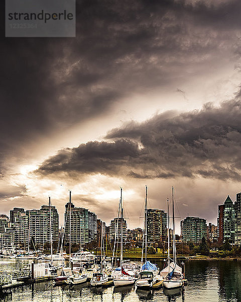 Wohngebäude und im Hafen vertäute Segelboote unter dunklen Wolken; Vancouver  British Columbia  Kanada