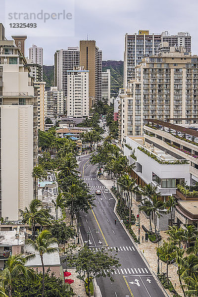 Blick in Richtung Osten auf die Kuhio Avenue in Waikiki  Honolulu  Hawaii  mit dem Diamond Head am Horizont  der zwischen den Gebäuden zu sehen ist. Der neue International Market Place mit seinen überdachten Parkplätzen ist im Vordergrund auf der rechten Seite zu sehen. Eröffnet im Jahr 2016; Honolulu  Oahu  Hawaii  Vereinigte Staaten von Amerika