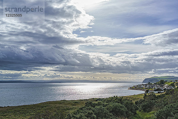 Sonnenlicht beleuchtet die Wolken und spiegelt sich auf dem ruhigen Meer entlang der schottischen Küste  Dornoch Firth; Balintore  Schottland