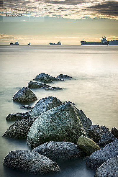 Schiffe im Pazifischen Ozean vor der Küste des Stanley Park mit Felsen im Vordergrund; Vancouver  British Columbia  Kanada