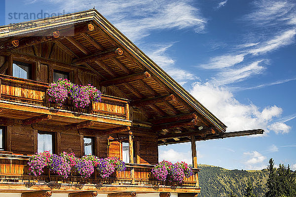 Nahaufnahme eines Holzchalets mit Blumenkästen und Balkonen mit blauem Himmel und Wolken im Hintergrund; Grainau  Bayern  Deutschland