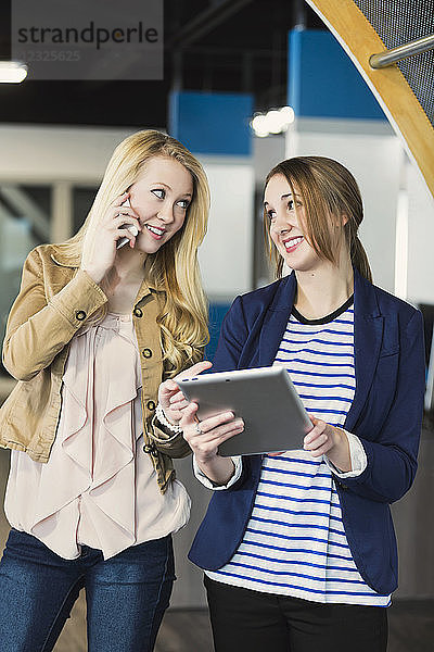 Zwei hübsche junge Geschäftsfrauen der Jahrtausendwende nutzen Technologie am Arbeitsplatz; Sherwood Park  Alberta  Kanada