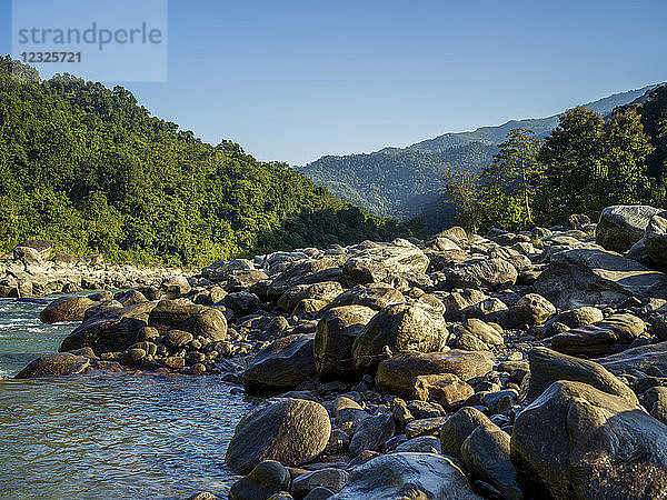 Große Felsen am Ufer eines im Himalaya fließenden Flusses mit üppigem Wald und blauem Himmel; Westbengalen  Indien