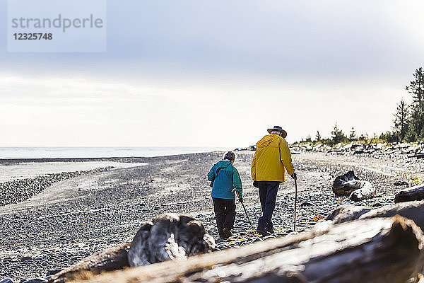 Ein älteres Paar wandert mit Wanderstöcken am Strand entlang der Küste  Meadow Mist Campground  Graham Island; Tlell  Haida Gwaii  British Columbia  Kanada