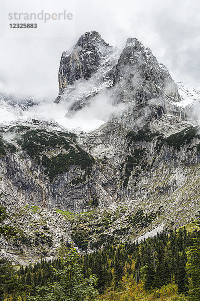 Zerklüfteter Berggipfel und Tal mit Gipfel  der durch eine Wolkendecke und Schnee kommt; Grainau  Bayern  Deutschland