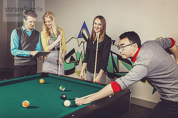 Eine Gruppe junger Geschäftsleute spielt in einer Arbeitspause eine Partie Billard; Sherwood Park  Alberta  Kanada