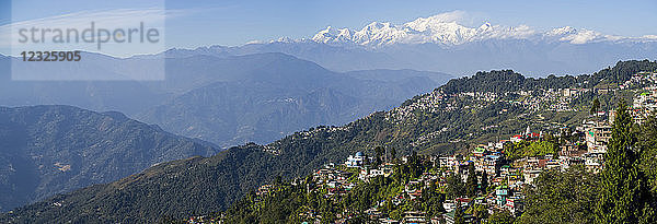 Stadt an einem Berghang mit den schroffen  schneebedeckten Gipfeln des Himalaya in der Ferne; Darjeeling  Westbengalen  Indien