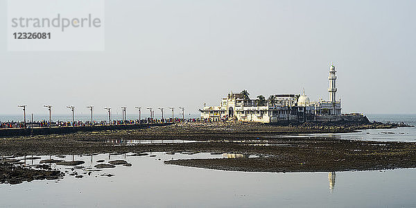 Touristen auf einer Straße  die zu einem Gebäude und einem Turm an der Küste führt  Arabisches Meer; Mumbai  Maharashtra  Indien