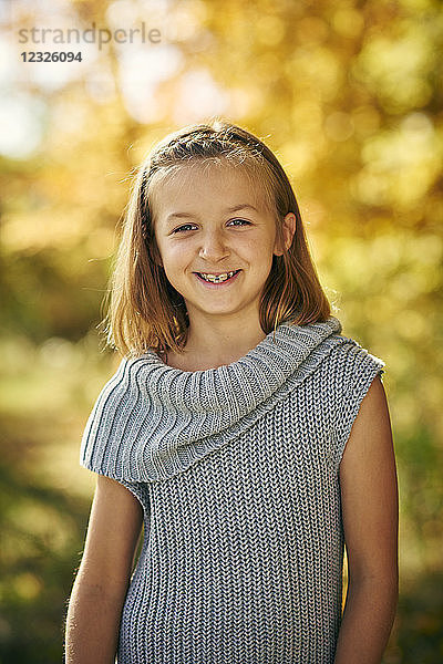 Porträt eines jungen Mädchens mit blondem Haar und Zahnspange  im Hintergrund herbstlich gefärbtes Laub; Ontario  Kanada