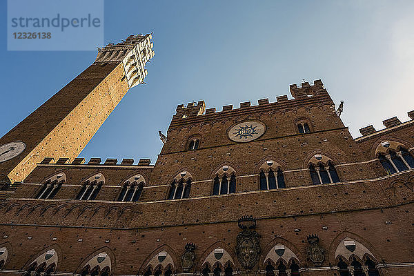 Niedriger Blickwinkel auf die Steinmauer des Rathauses mit Mangia-Turm und blauem Himmel; Siena  Toskana  Italien