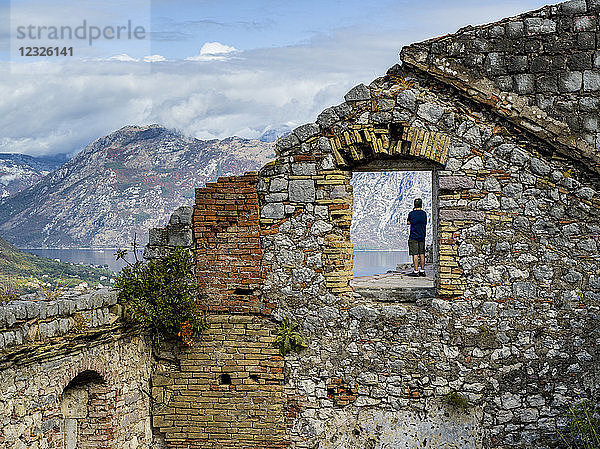 Ein männlicher Tourist steht an der Burg von San Giovanni in Kotor und blickt auf das Wasser unter ihm; Kotor  Montenegro