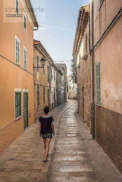 Frau  die eine schmale Straße hinuntergeht; Alcudia  Mallorca  Balearische Inseln  Spanien