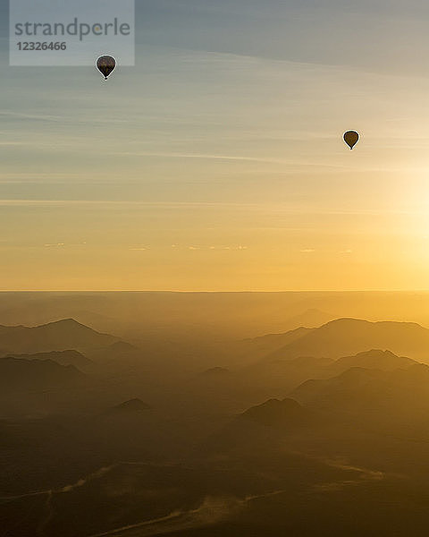 Silhouette von Heißluftballons im goldenen Himmel über den Sanddünen bei Sonnenaufgang in der Namib-Wüste; Sossusvlei  Hardap Region  Namibia