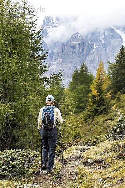 Wanderin auf alpinem Weg mit wolkenverhangenen Bergen im Hintergrund; Sexten  Bozen  Italien