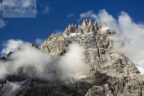 Zerklüftete Bergspitze  die aus den Wolken mit blauem Himmel auftaucht; Sexten  Bozen  Italien