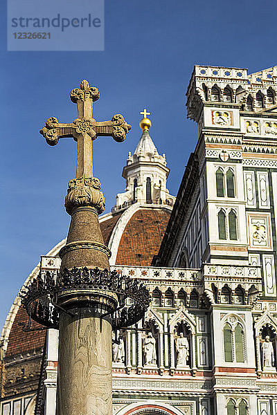 Steinkreuz mit der dekorativen Kuppel und Fassade der Kathedrale von Florenz mit blauem Himmel; Florenz  Toskana  Italien