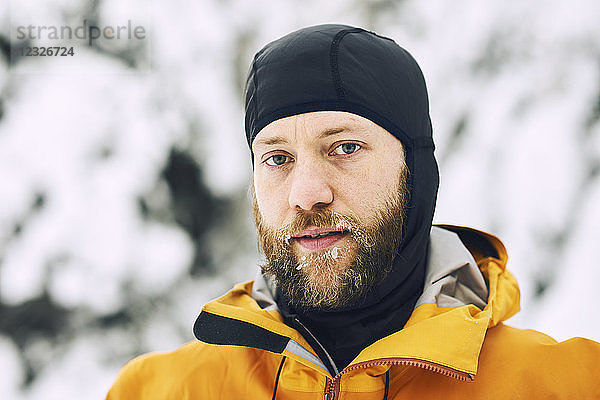 Porträt eines Mannes mit frostigem Bart und Kopfbedeckung vor einem verschneiten Hintergrund; British Columbia  Kanada
