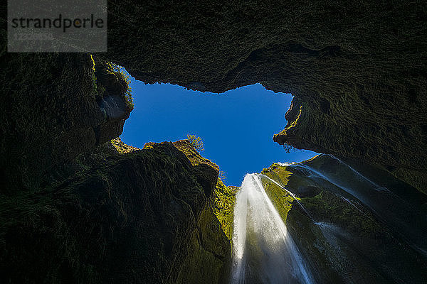 Blick auf einen kleinen Wasserfall in einem großen Loch in der Nähe des Seljalandsfoss; Island