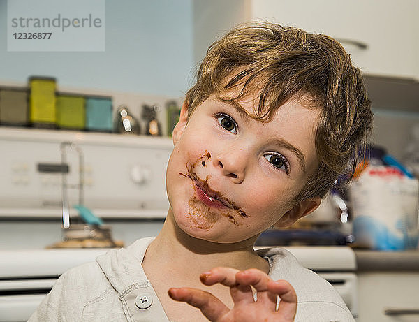 Ein grinsender Junge leckt sich die Finger und wird schmutzig  nachdem er Fudge gemacht hat; Langley  British Columbia  Kanada