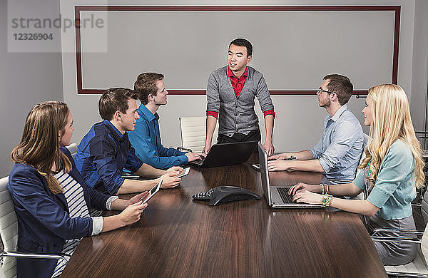 Ein junger Geschäftsmann spricht zu einer Gruppe junger Berufstätiger in einem Konferenzraum in einem Geschäftshaus; Sherwood Park  Alberta  Kanada