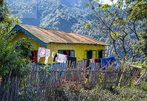 Ein leuchtend gelbes Haus mit blauen Verzierungen und einer Wäscheleine  die draußen im Himalaya hängt; Westbengalen  Indien