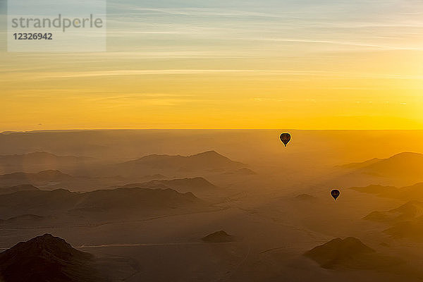 Silhouette von Heißluftballons im goldenen Himmel über den Sanddünen bei Sonnenaufgang in der Namib-Wüste; Sossusvlei  Hardap Region  Namibia