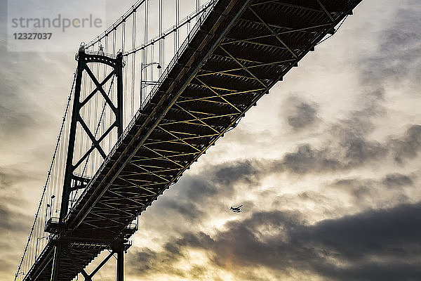 Niedriger Blickwinkel auf eine Brücke bei Sonnenuntergang mit einem Flugzeug in der Ferne; Vancouver  British Columbia  Kanada