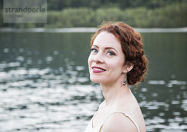 Porträt einer Frau mit roten Haaren und einem See im Hintergrund; British Columbia  Kanada