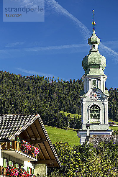Dekorativer Kirchturm in einem Bergdorf mit Blumenkästen und blauem Himmel; Toblach  Bozen  Italien