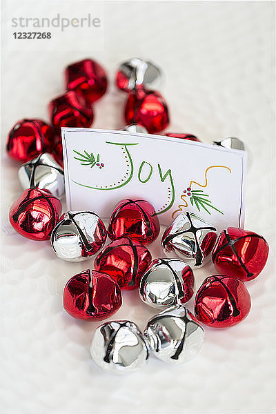 Rote und silberne Glocken mit einem Schild mit der Aufschrift Freude für eine Weihnachtsdekoration