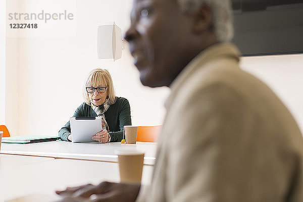 Senior businesswoman using digital tablet in conference room meeting