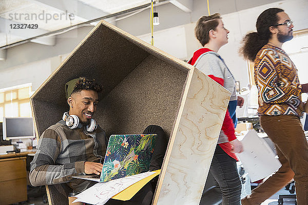 Creative businessman working at laptop in cubby