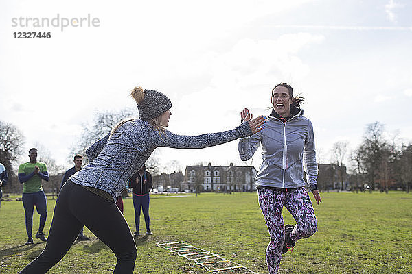 Women high-fiving  exercising in park