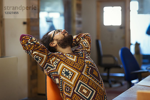 Creative businessman stretching at desk in office