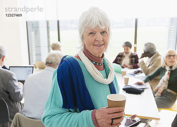 Portrait confident senior businesswoman drinking coffee in meeting