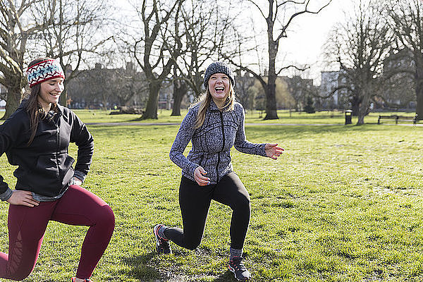 Smiling  confident women doing lunges in sunny park