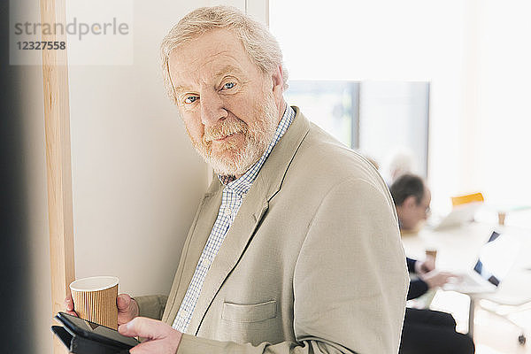 Portrait confident senior businessman with digital tablet