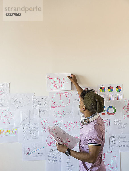 Creative businessman hanging paperwork on office wall