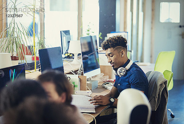 Creative businessman working at computer in open plan office