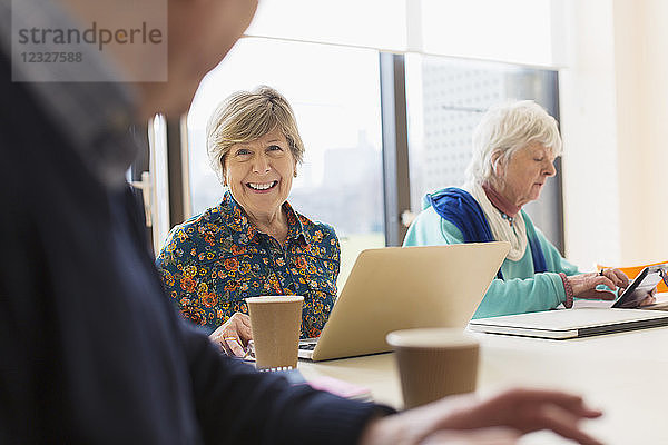 Senior businesswoman using laptop in conference room meeting