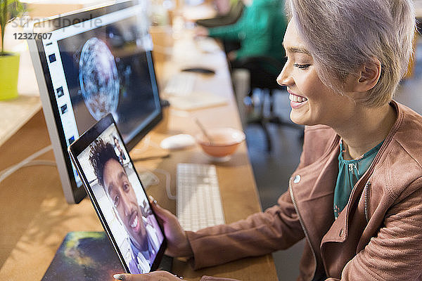 Creative businesswoman video chatting with colleague on digital tablet in office