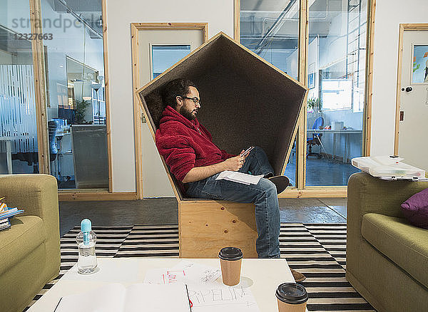 Creative businessman using smart phone in office cubby